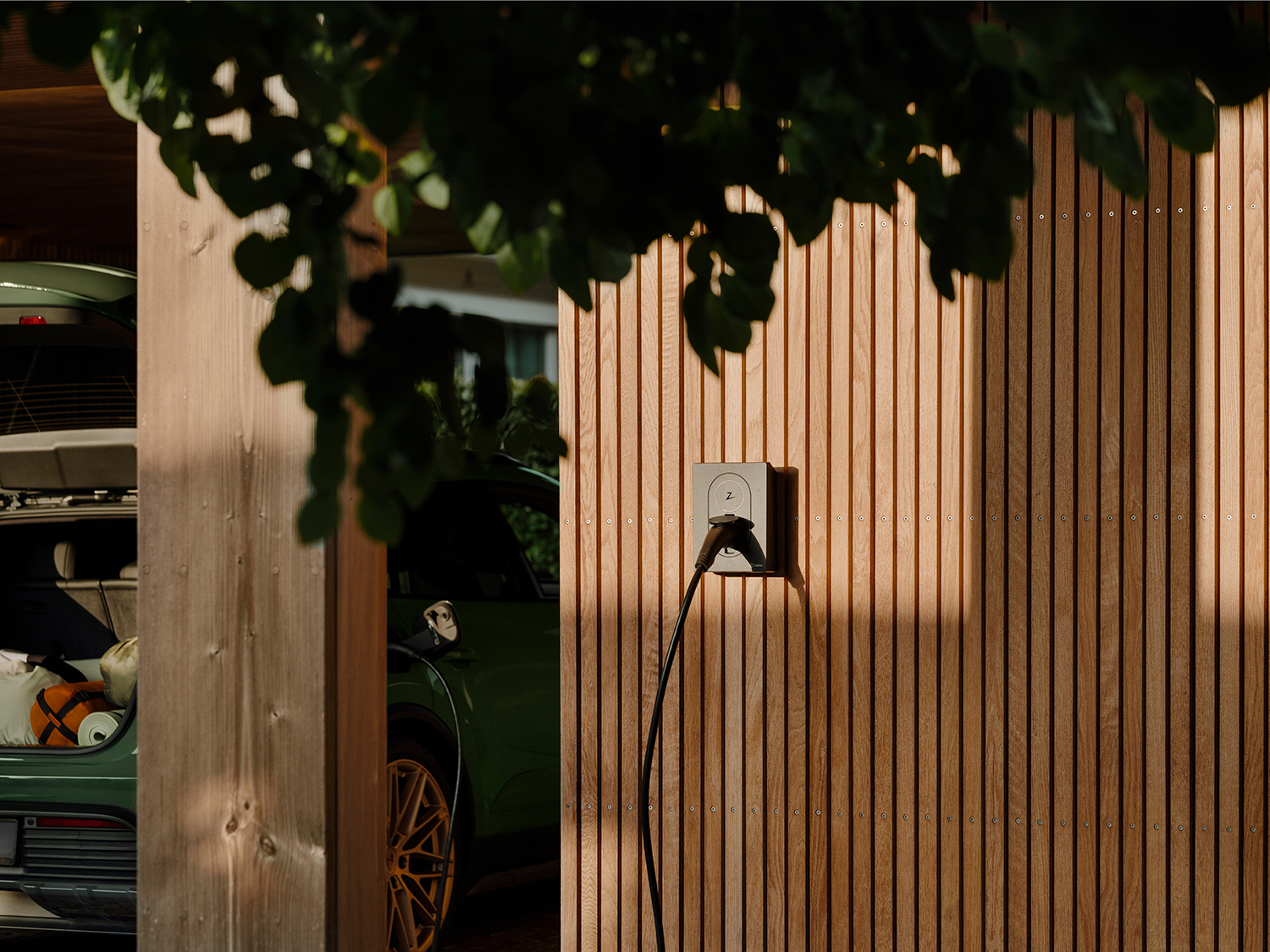 Zaptec laadpaal aan een houten gevel met warm avondlicht — thuisladen in stijl